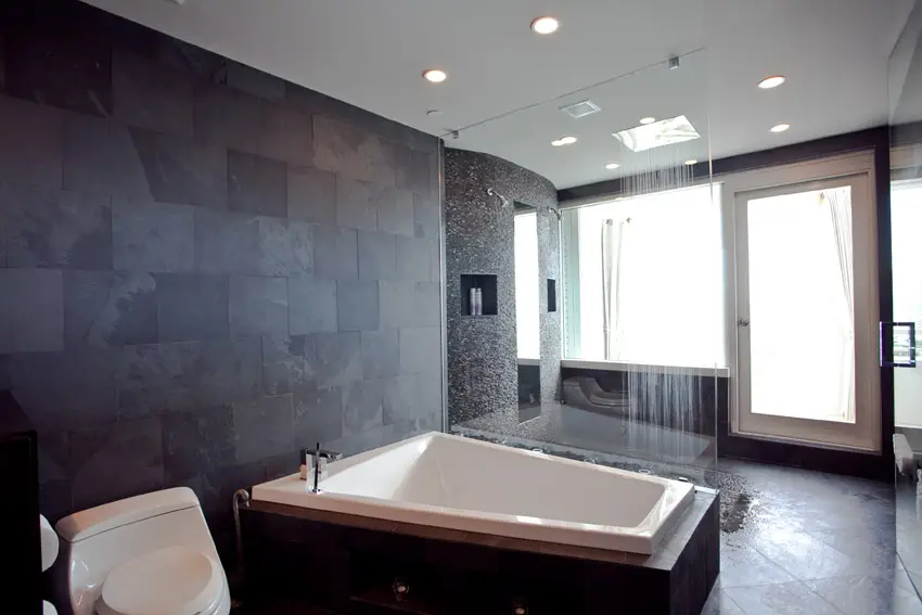 Resort style bathroom with dark accent wall and huge bathtub