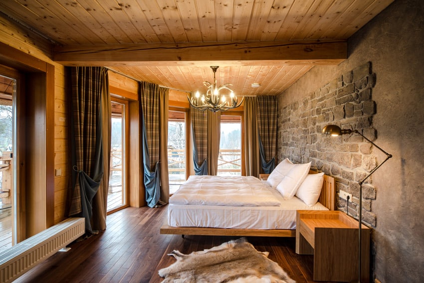 Rustic wood ceiling and stone accent wall in master bedroom