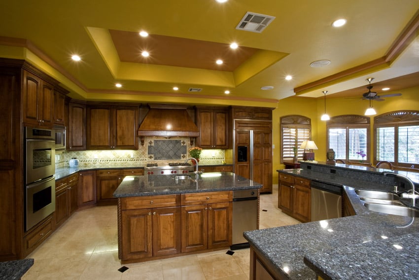 Yellow ceiling kitchen with rich wood cabinetry and two level granite countertop