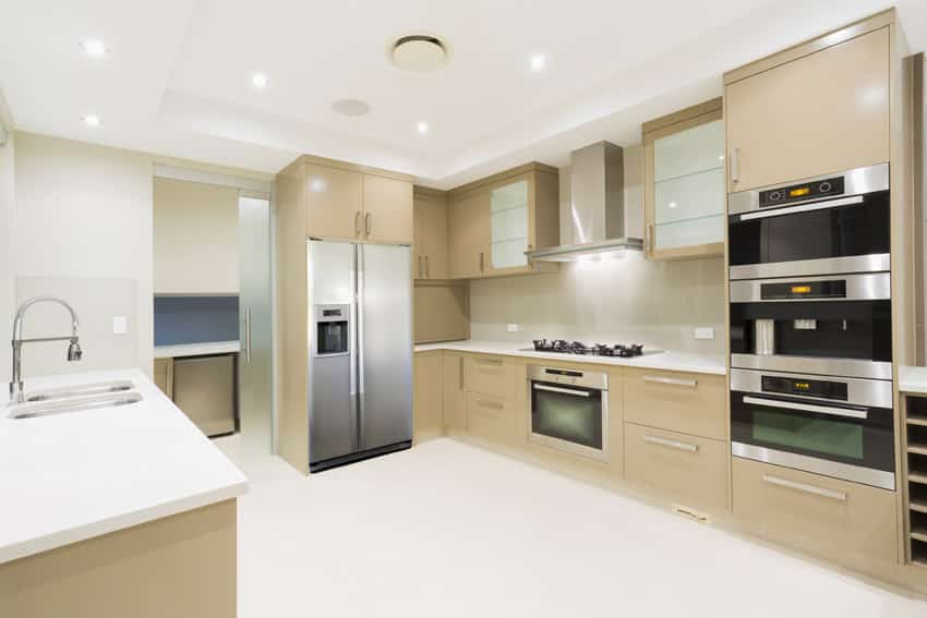 Bright new modern kitchen with white counter top and beige cabinets