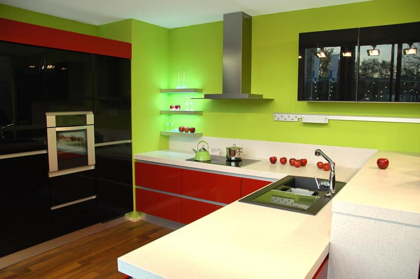 Green walls, black overhead cabinets and red drawers and quartztite countertop