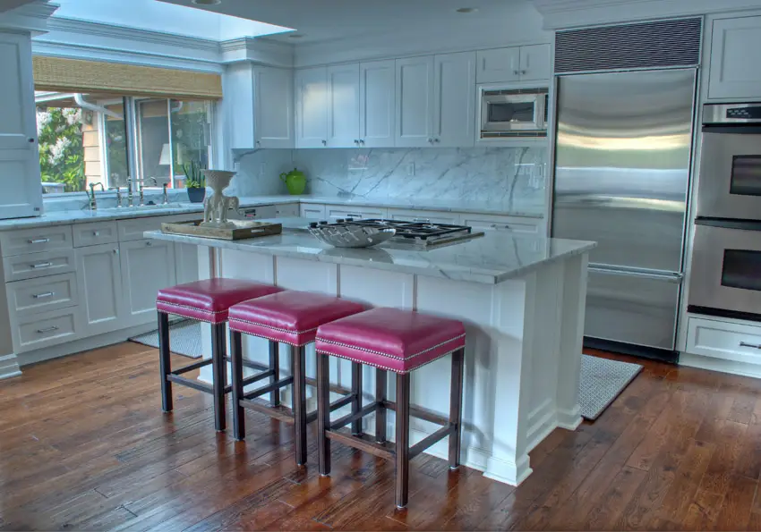 Kitchen with bright pink stools and marble backsplash