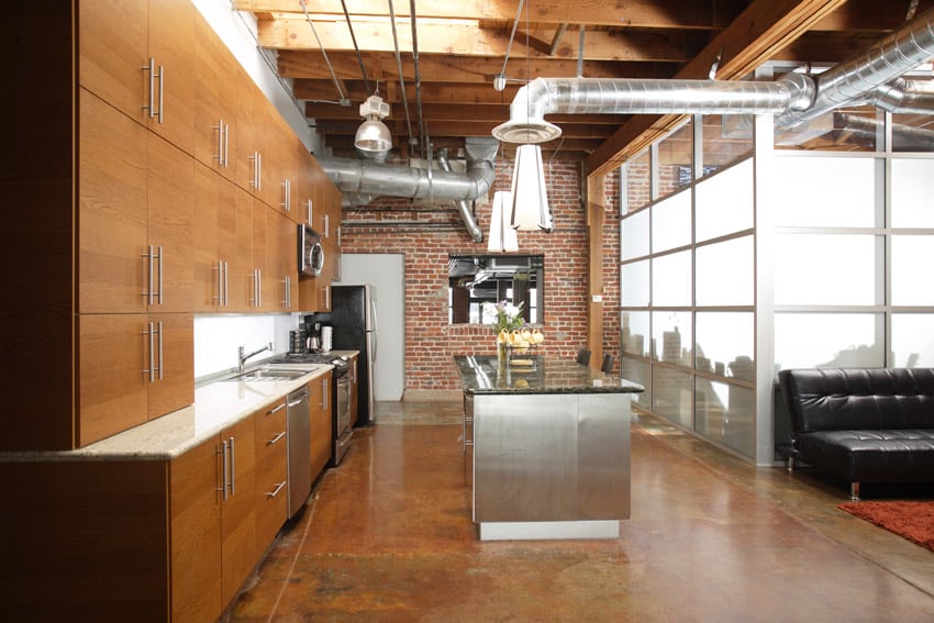Industrial style kitchen design in loft with brick wall, concrete flooring and exposed duct work
