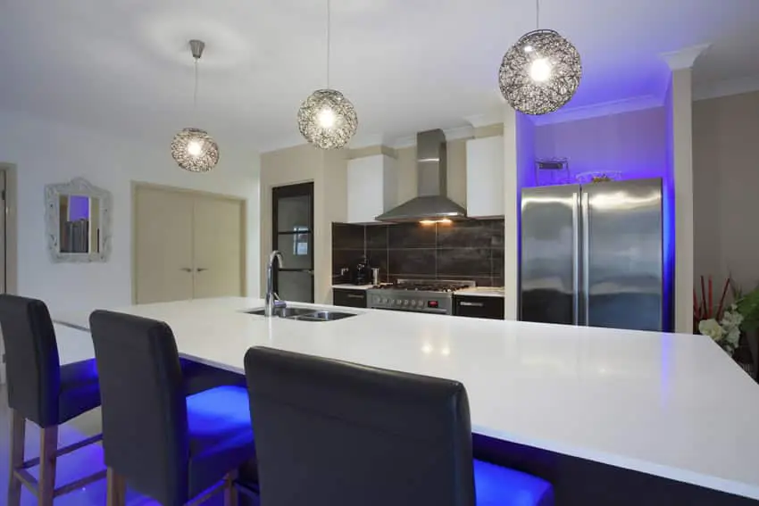 Modern kitchen with large island, wire globe lighting, and neon backlights.