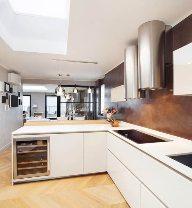 L-shape kitchen with plain white cabinets ans chevron pattern flooring