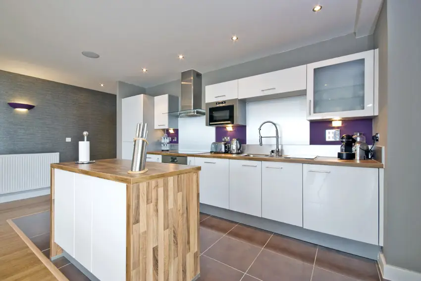 Kitchen with small wood island with silver and violet backsplash colors