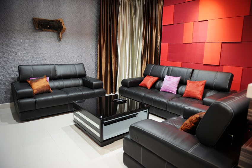 Bright red and orange accent wall paired with black couches