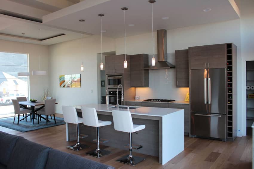 Kitchen with white waterfall island, four-seater dining table and chairs and wine racks