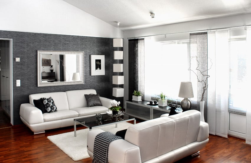 Modern living space with black wallpaper, wood flooring and white couches