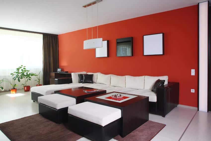 Modern room with red wall, a pair of ottomans with black body and art installation in the walls