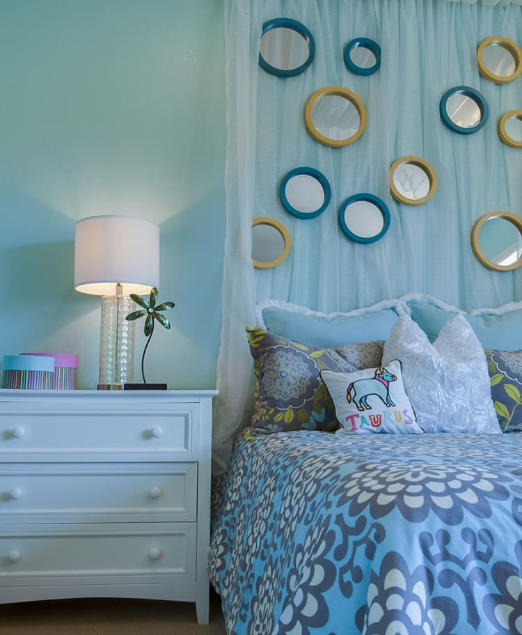 Pretty blue girls bedroom with circular wall mirrors
