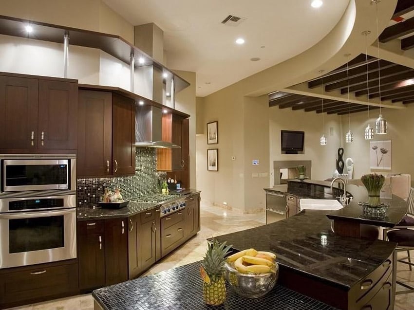 Curved luxury kitchen with open layout, dark cabinets and tile backsplash