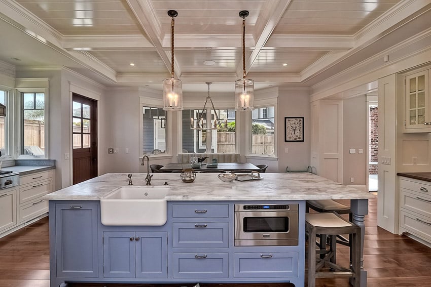 Kitchen with blue island, farmhouse sink and cabinets with steel knobs