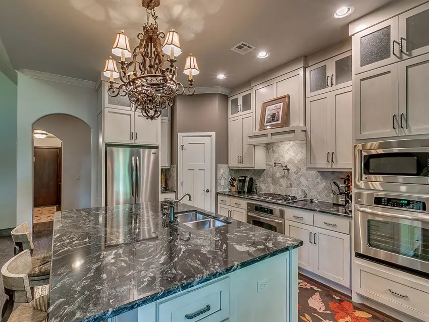 Kitchen with classic chandelier and rectangular tiles placed diagonally as backsplash