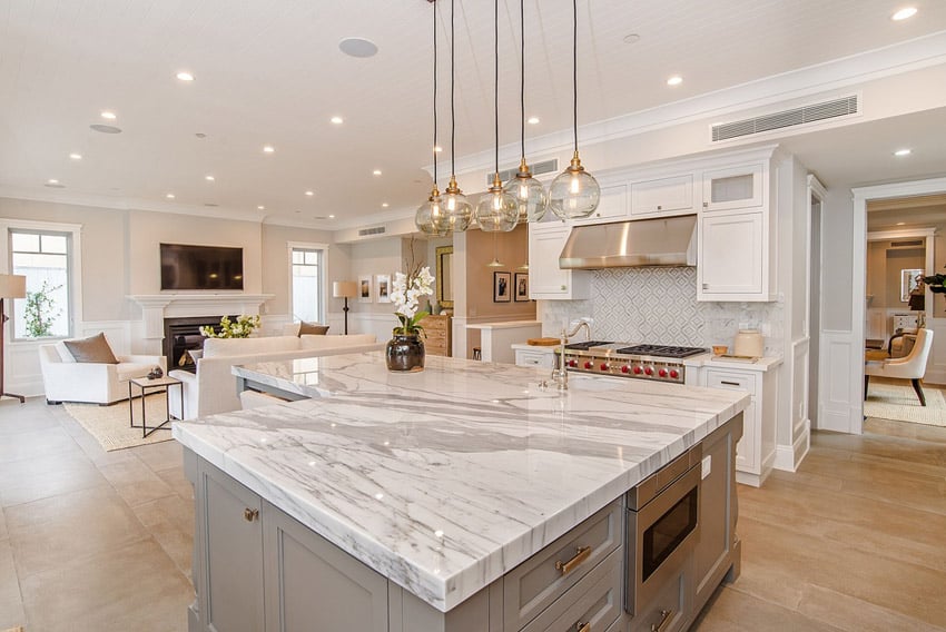 L shape kitchen with white cabinets and gray island with marble counters