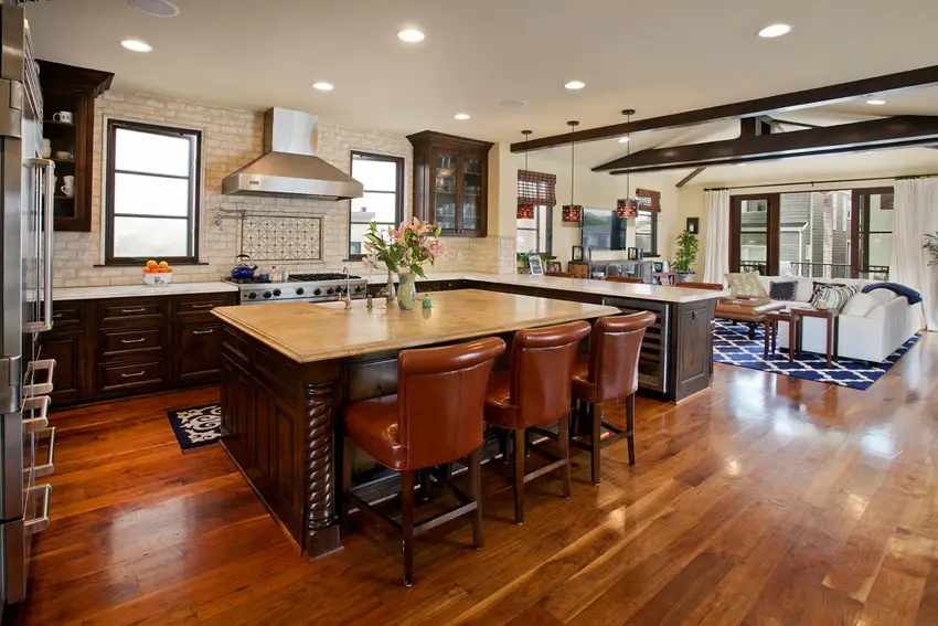 Open floor plan with U-shaped kitchen, upholstered chairs and brick backsplash