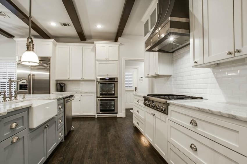 White cabinet kitchen with offcolor island and exposed beam ceiling