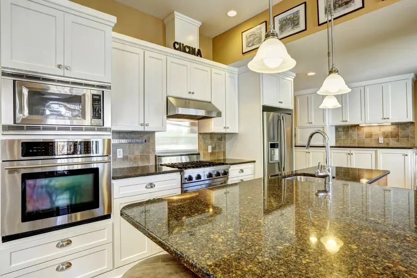 Yellow walls, silver pull on cabinets with white paint finish and ceiling lights 