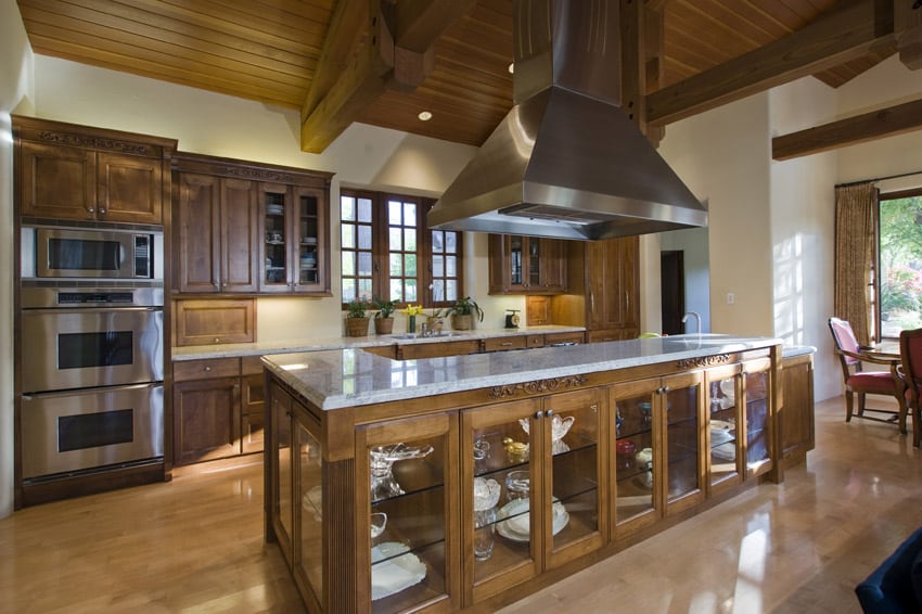 Wooden kitchen design with large island and large stainless oven hood