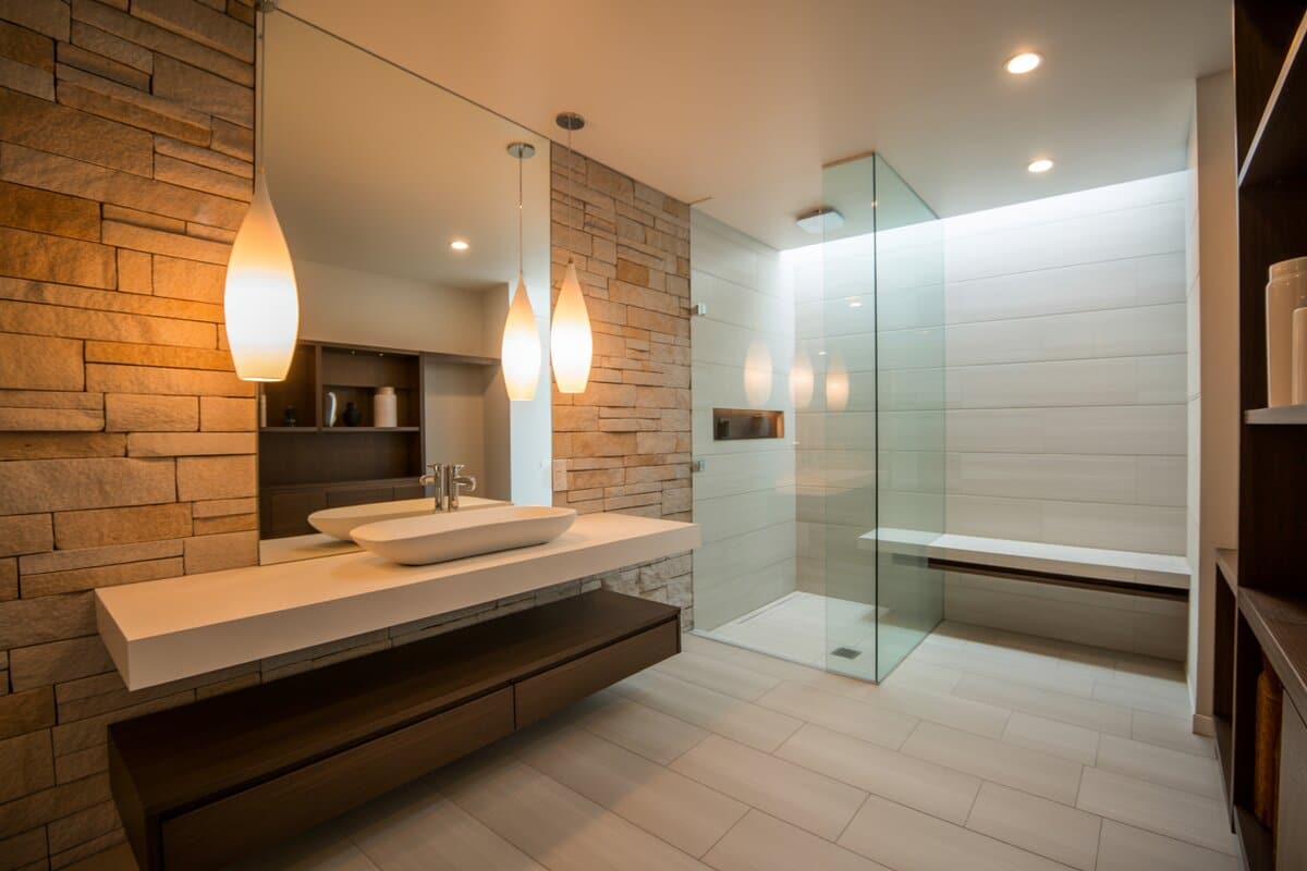 Twin teardrop pendant lights glowing against a stacked stone wall above a floating vanity