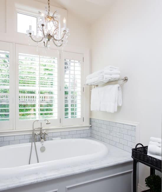 Chandelier over bathtub in bright white bathroom