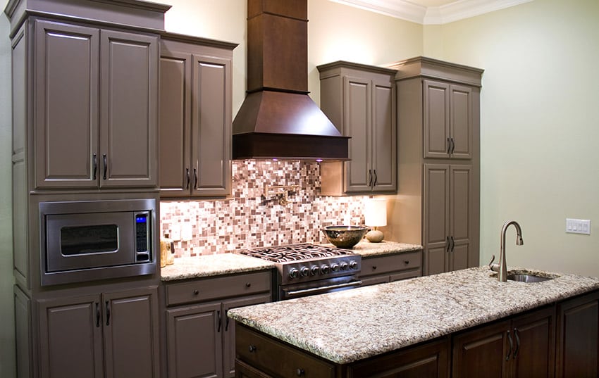 Compact kitchen with granite counter island, dark cabinets and mosaic tile backsplash