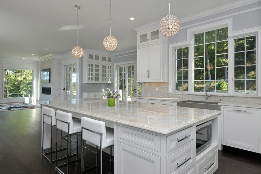 White contemporary kitchen with sugar beige marble counters and globe pendant lighting