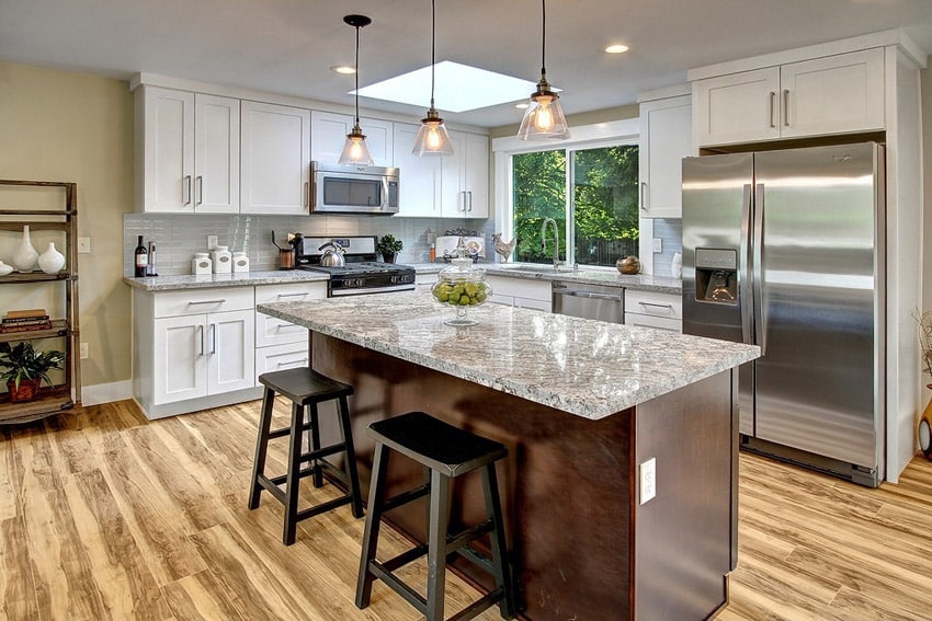 L shape kitchen with white cabinets, island , light granite counters, and pendant lights