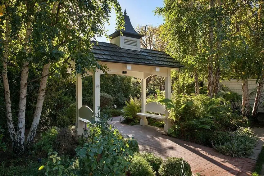 Red paver walkway through garden arbor