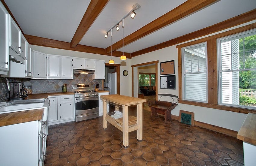 Kitchen with exposed wood beams, hexagonal floor tiles and large windows