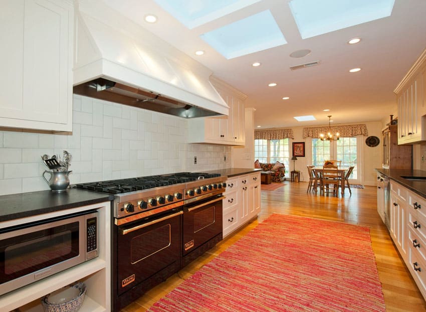 Traditional galley kitchen with white cabinets and skylight