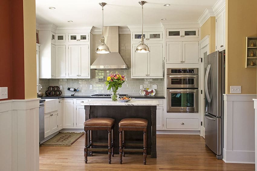 Kitchen with island with dark walnut finish, marble top and stools with leather seating