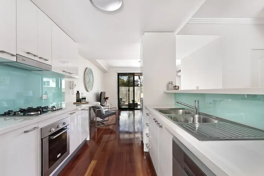 White modern galley kitchen with glass aqua backsplash