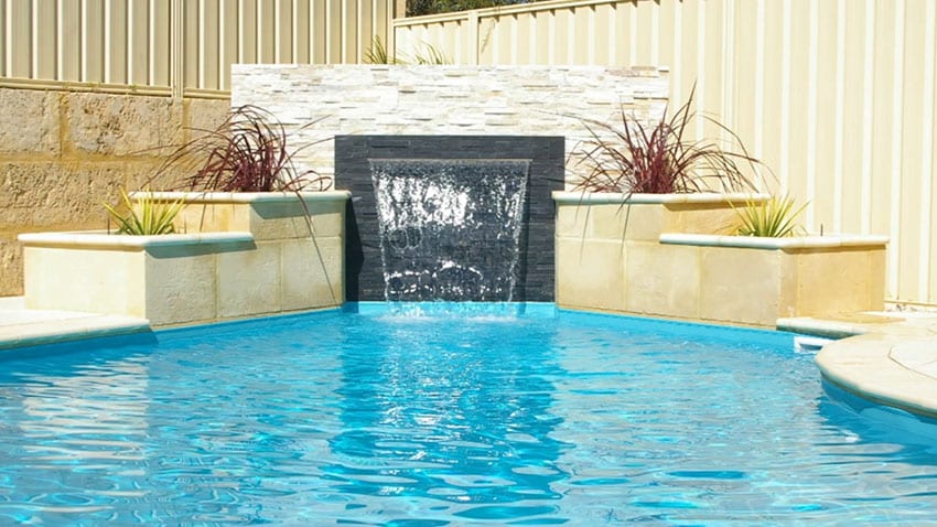 Pool with beadboard fence, stacked stone wall with dark stone inlay