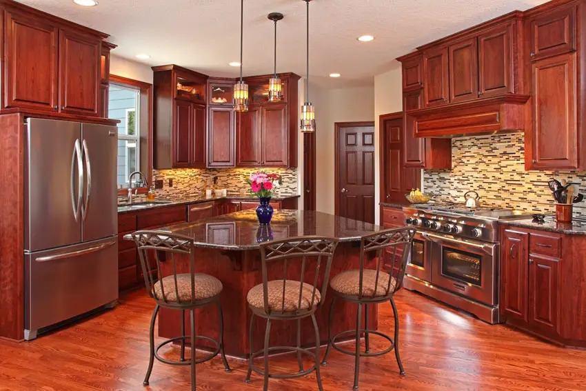 Kitchen with wrought iron chaiers, wood plank floors and hanging lights