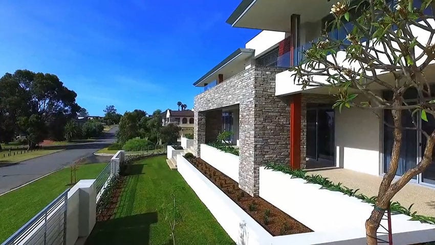 Front yard of modern house with stone walls and balcony