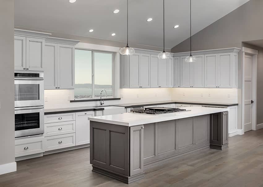 Kitchen layout with island and white cabinets and two types of countertops