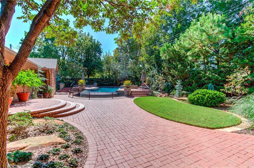Landscaped patio area with red paver bricks leading to swimming pool
