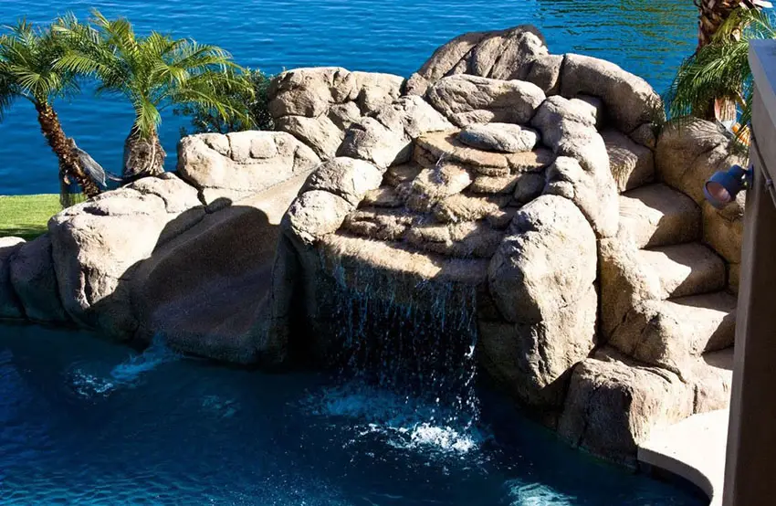 Large rock waterfall water feature in swimming pool