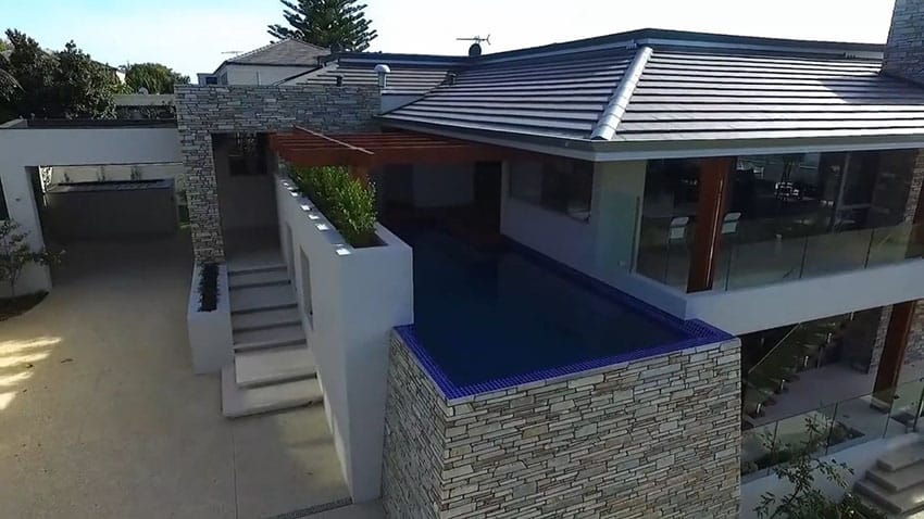 Pool with blue tiles, wooden trellis and glass railings