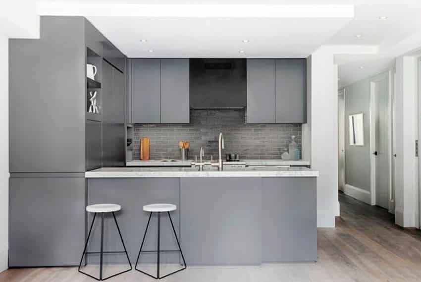 Modern kitchen with gray cabinets and gray brick backsplash with marble countertops