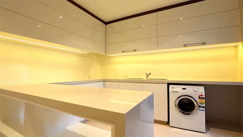 Modern laundry in kitchen with high gloss white lacquer cabinets