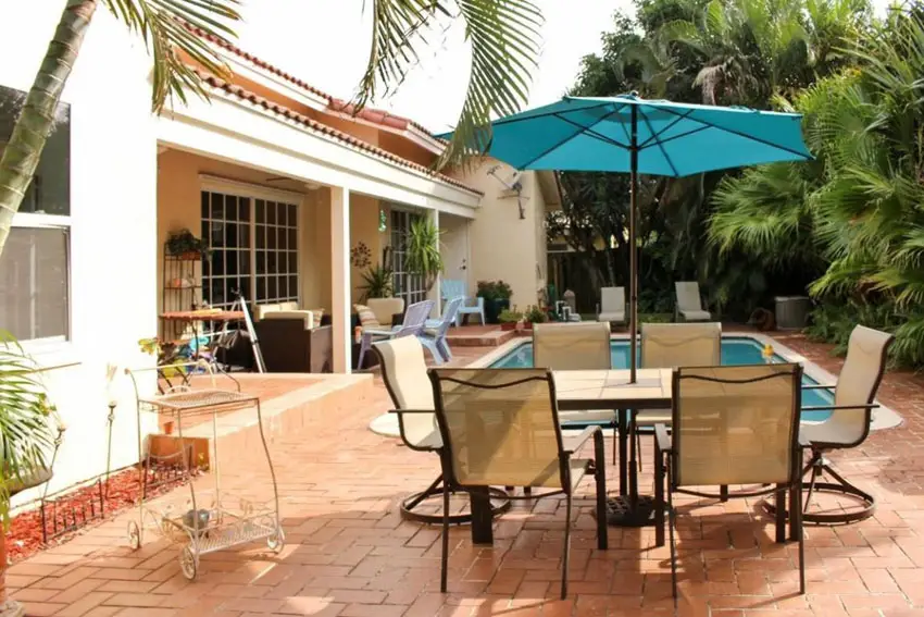 Poolside paver patio with outdoor table and umbrella