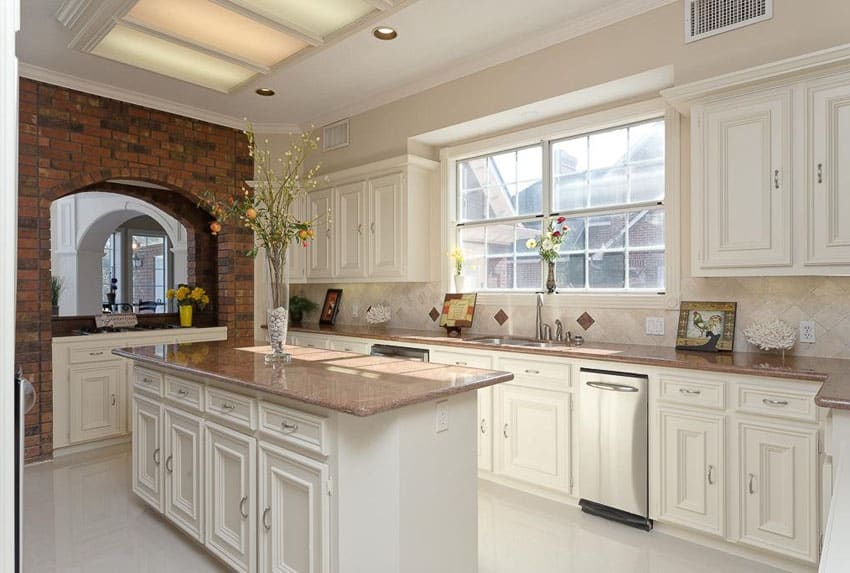 Traditional white kitchen with brick arch and travertine backsplash