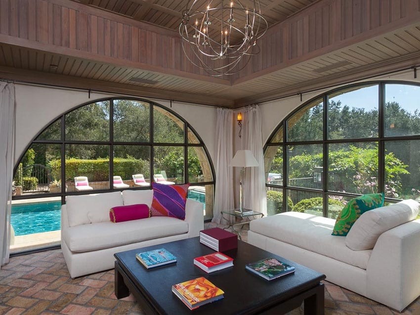 Tuscan sunroom with modern chandelier and swimming pool view