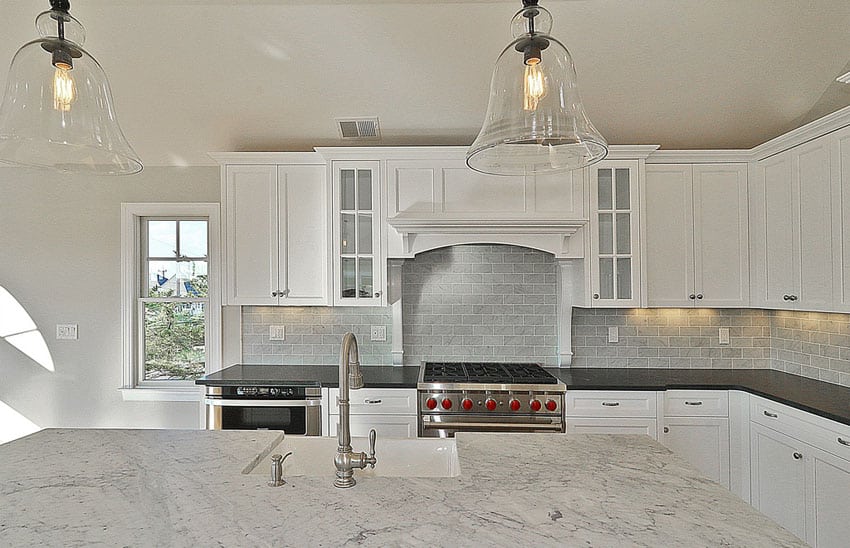 White kitchen with marble counters and brick subway tile backsplash