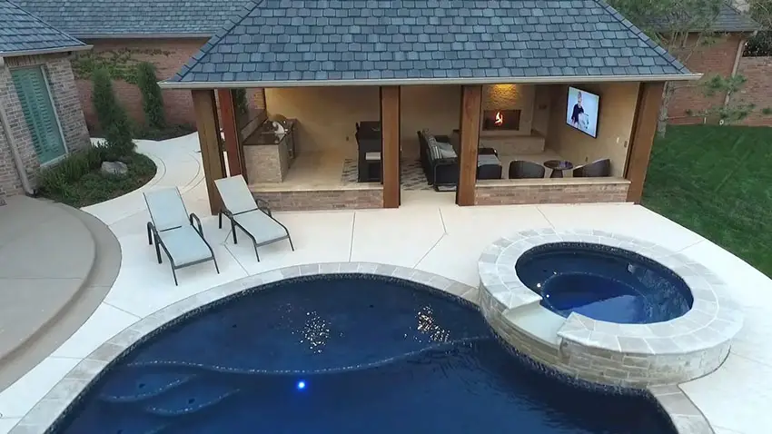 backyard cabana with kitchen, fireplace, tv, pool and spa