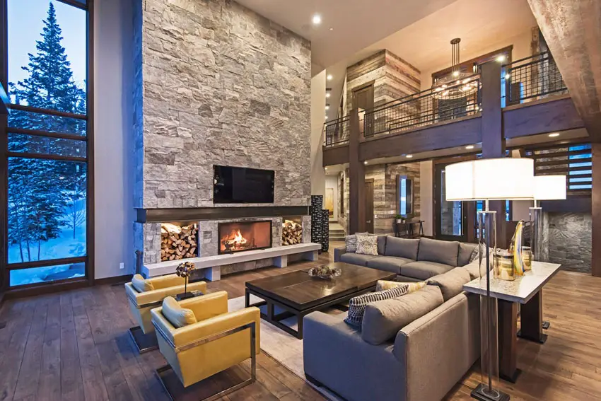 Room with matte hickory floors, stone cladding fireplace wall and sectional sofa