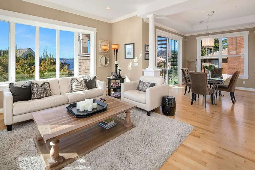 Large windows, white leather sofa, oak coffee table and beige area rug