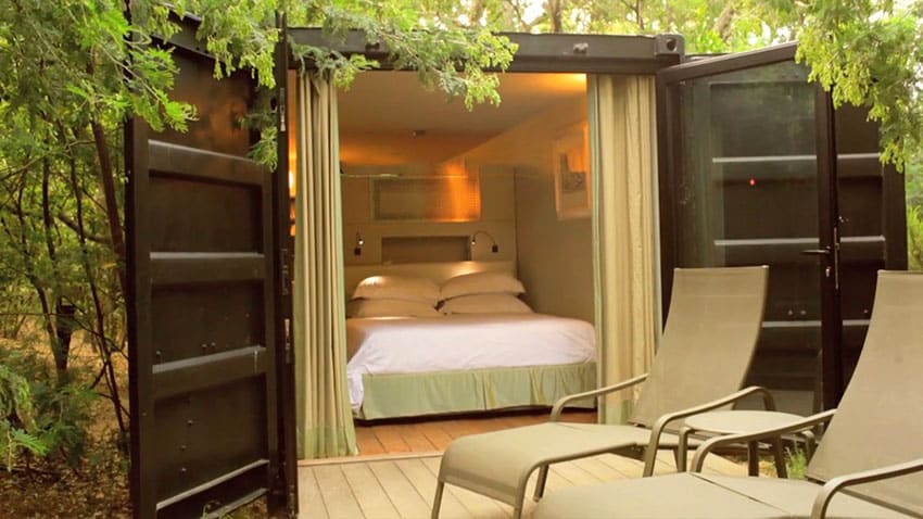 Shipping container house bedroom with open doors to outside garden and deck